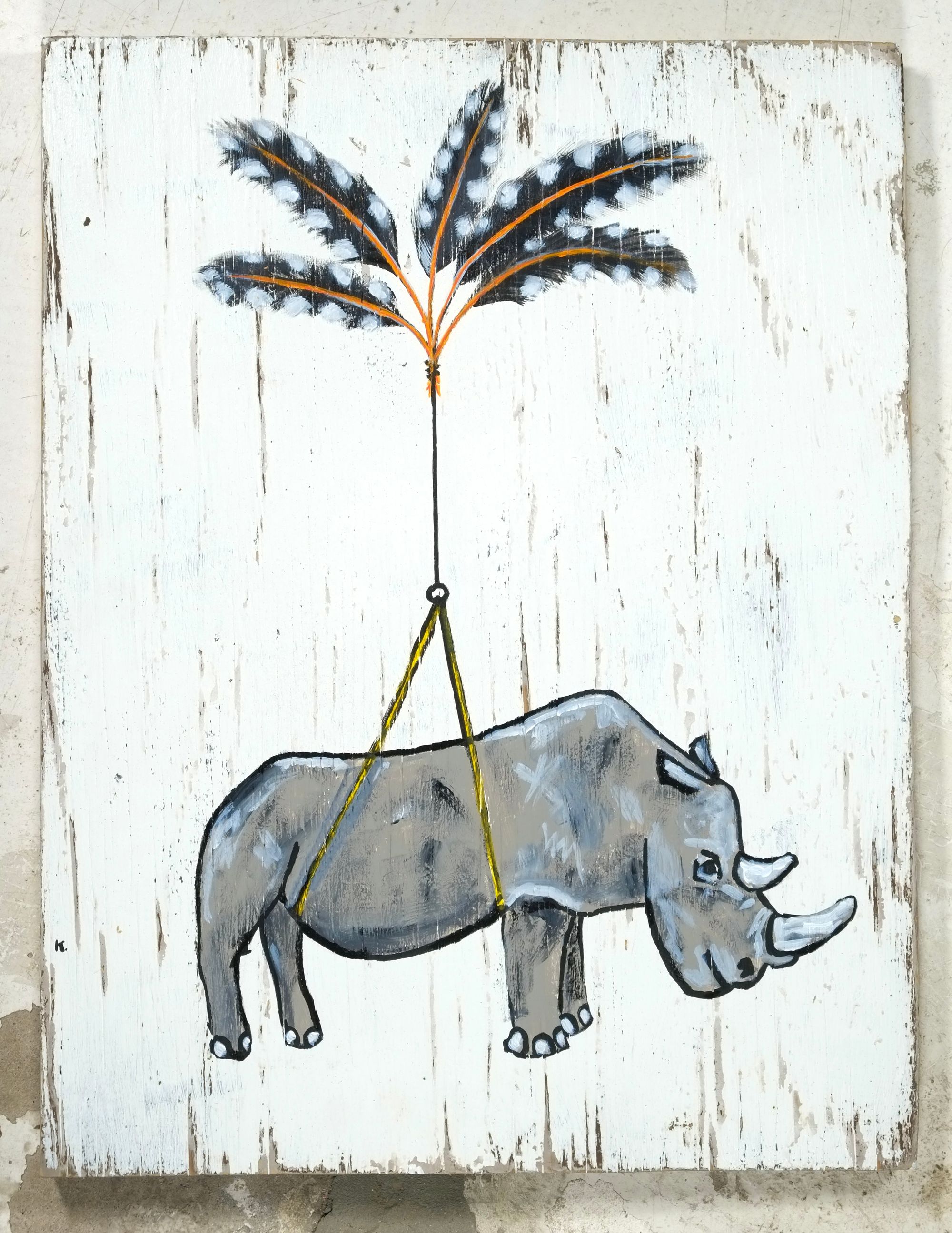 Acrylic painting on weathered white found wood of a gray rhino suspended by a yellow harness from a bundle of spotted black-and-white flicker feathers.