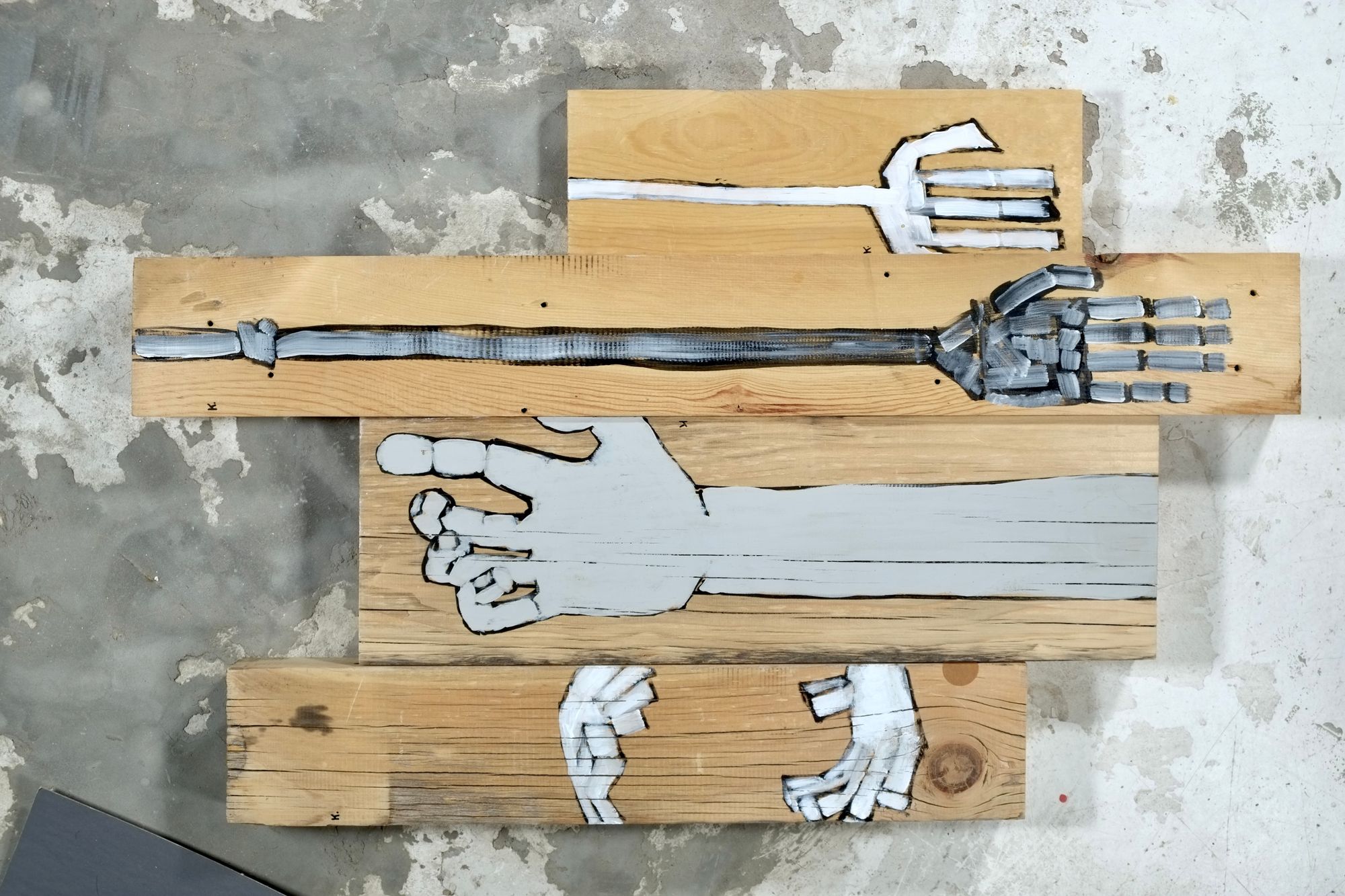 Acrylic painting on stacked found wood boards depicting white and gray hands and arms in various poses, including a skeletal mechanical arm and outstretched open hands.