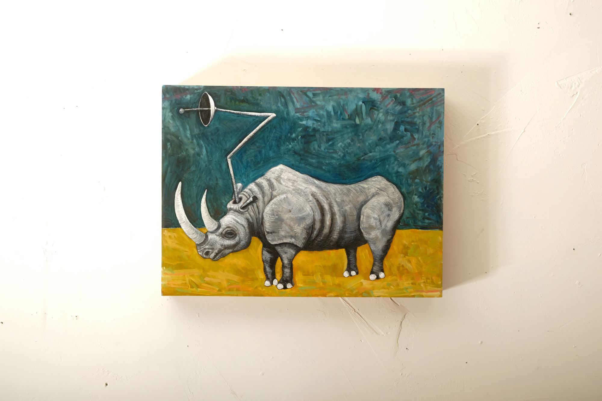 Oil on gesso panel painting of a gray rhinoceros with a satellite dish antenna mounted on its back, standing on yellow ground against an expressive teal-green background.