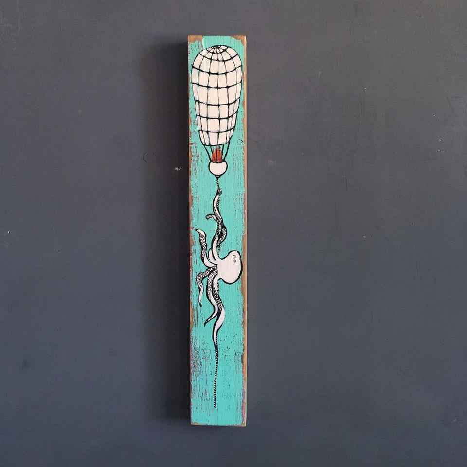 Mixed media painting on a tall narrow piece of found wood showing a white octopus dangling from a hand-sewn hot air balloon on a turquoise background.