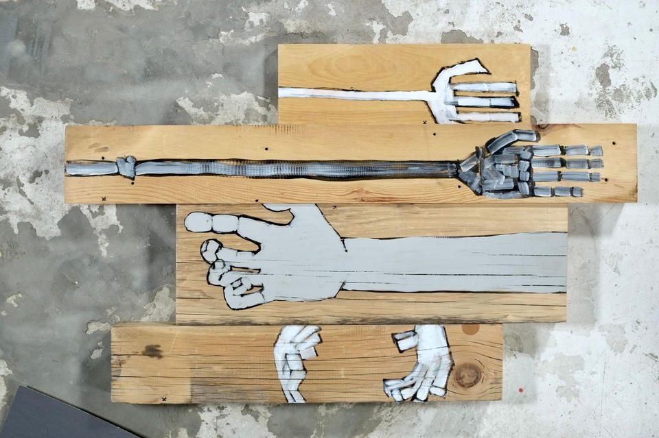 Acrylic painting on stacked found wood boards depicting white and gray hands and arms in various poses, including a skeletal mechanical arm and outstretched open hands.