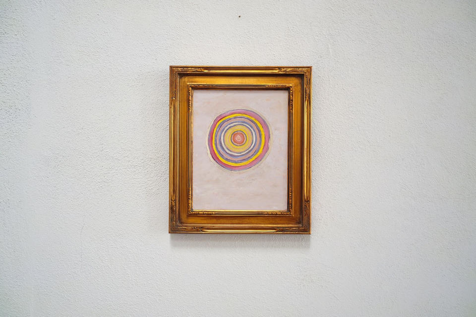 The painting Autumnal Twilight displayed in its gold frame on a white textured wall, showing the work at a distance to convey its installed scale.