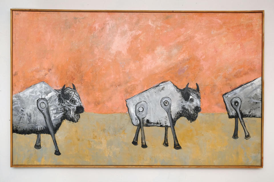 Oil on linen painting of three gray mechanical bison with boxy angular bodies and wind-up key-like legs, grazing on a yellow-ochre plain beneath a warm coral-orange sky.