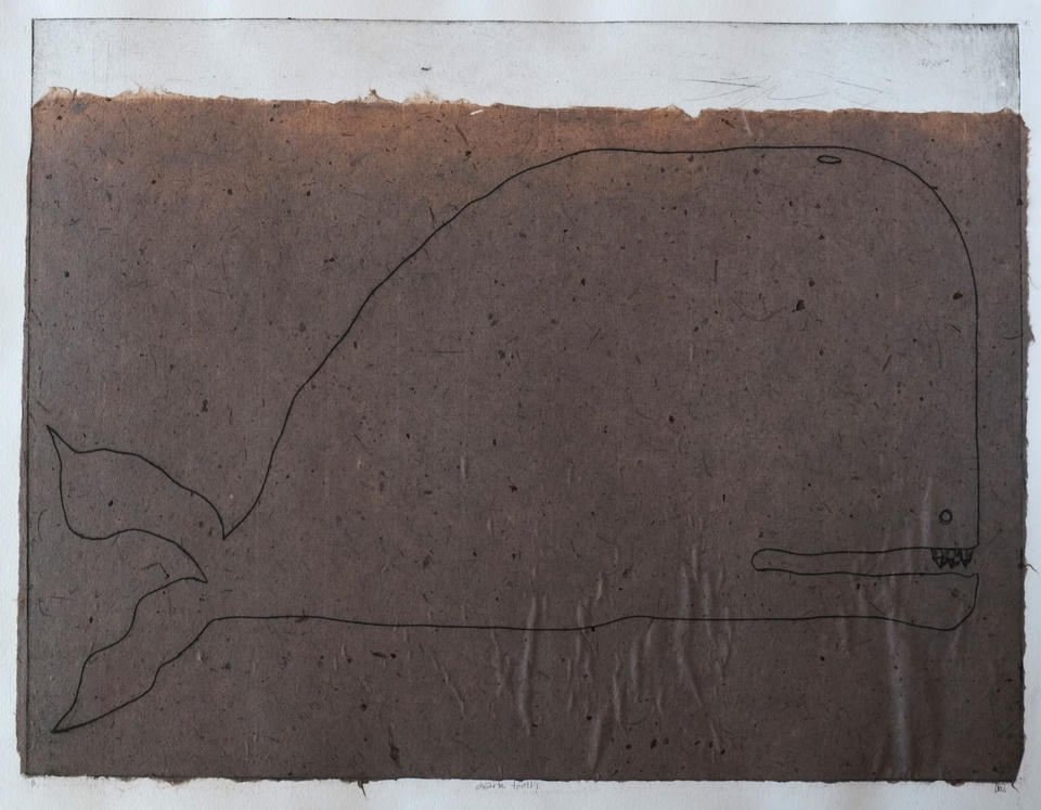 Intaglio print of a whale rendered in simple contour lines on dark brown handmade paper, with small crystalline teeth visible in its open jaw and a forked tail at left.